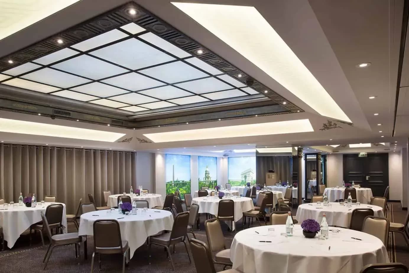 Reception room with a decorated ceiling and round tables set with white cloths