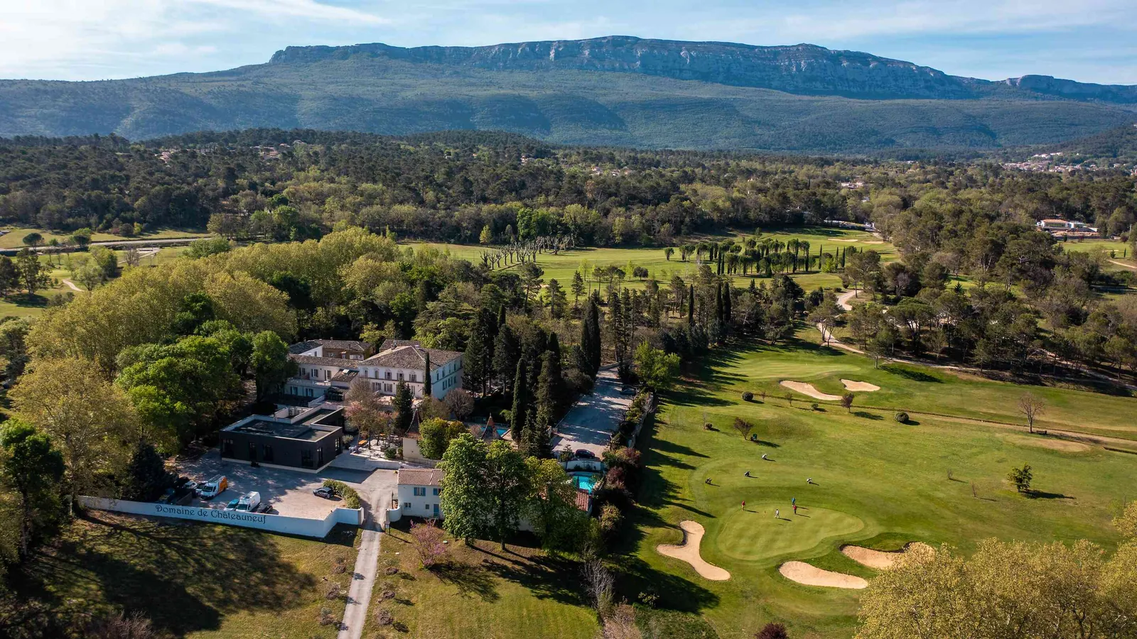 Aerial view of Bastide des Collines Dorées with its golf course, pool and mountain ridge in the distance