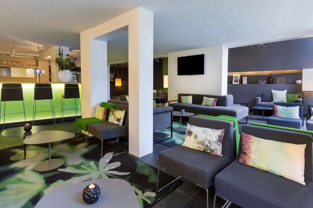 Lounge area of the Best Western Plus Hôtel du Parc Chantilly with grey sofas, green bar stools and a flat-screen TV