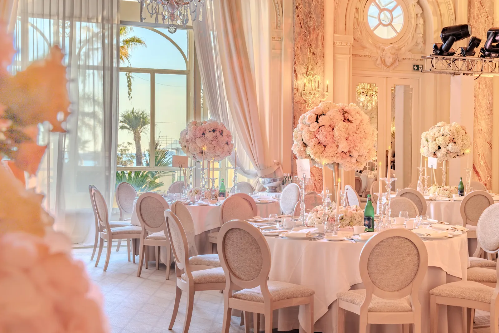 Grand salon dressed with pink floral centrepieces for a wedding dinner at Carlton Cannes, Cannes