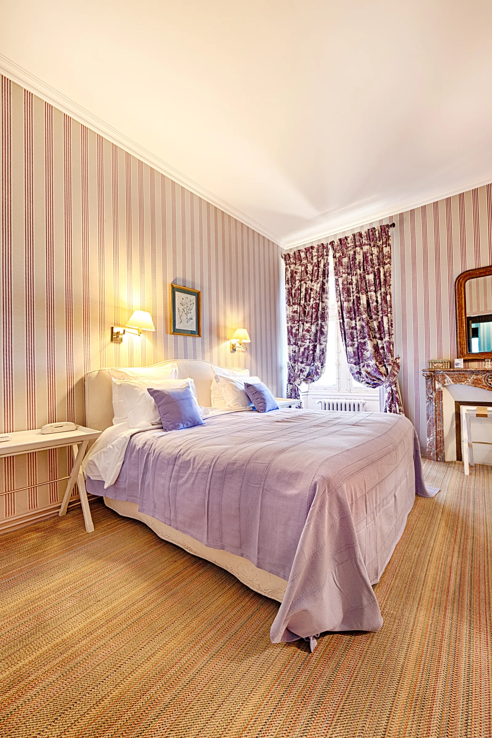 Guest room with striped wallpaper, lilac bedding and wall lamps at Château de la Bourdaisière, Loire Valley