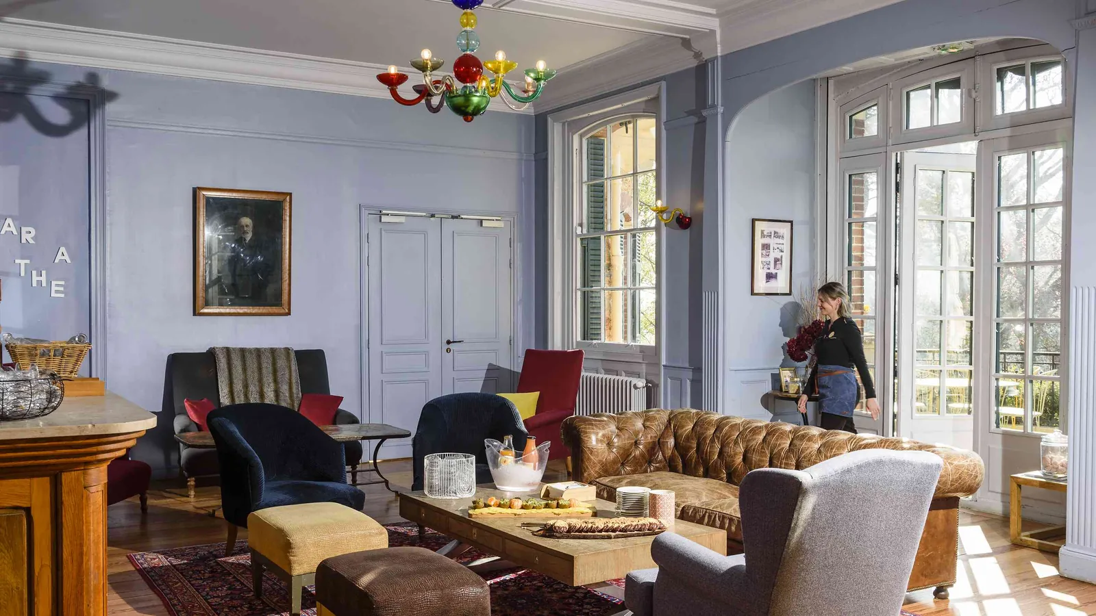 Lounge with a chandelier, portrait and deep sofa at Château des Berges Sereines, Yvelines