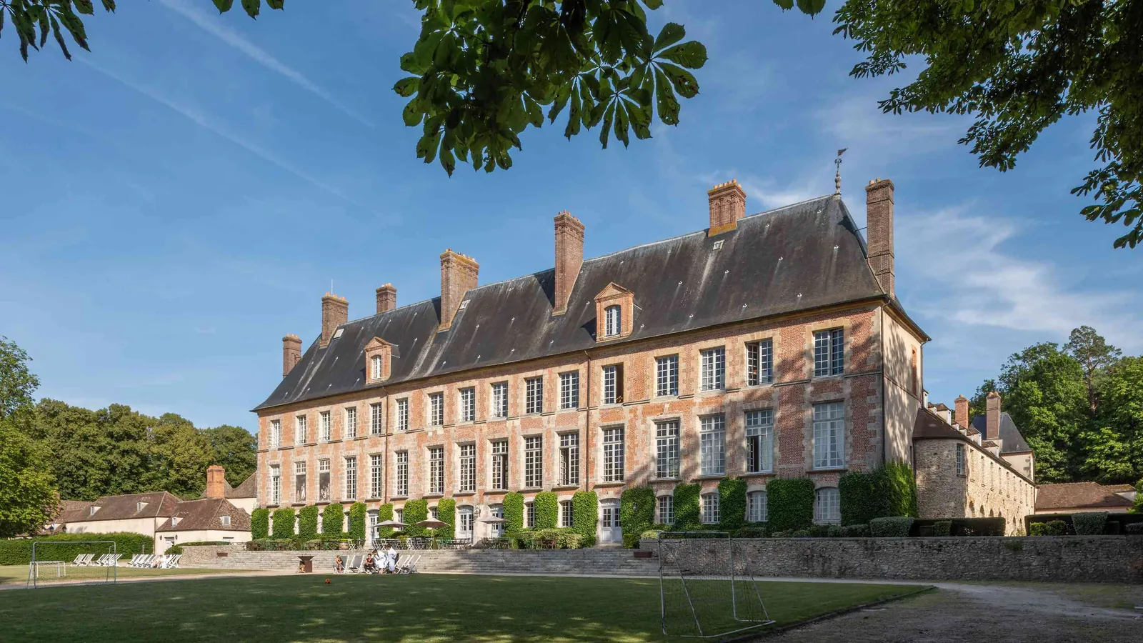 Classic château facade with a lawn and chestnut tree at Château des Grandes Perspectives, west of Paris