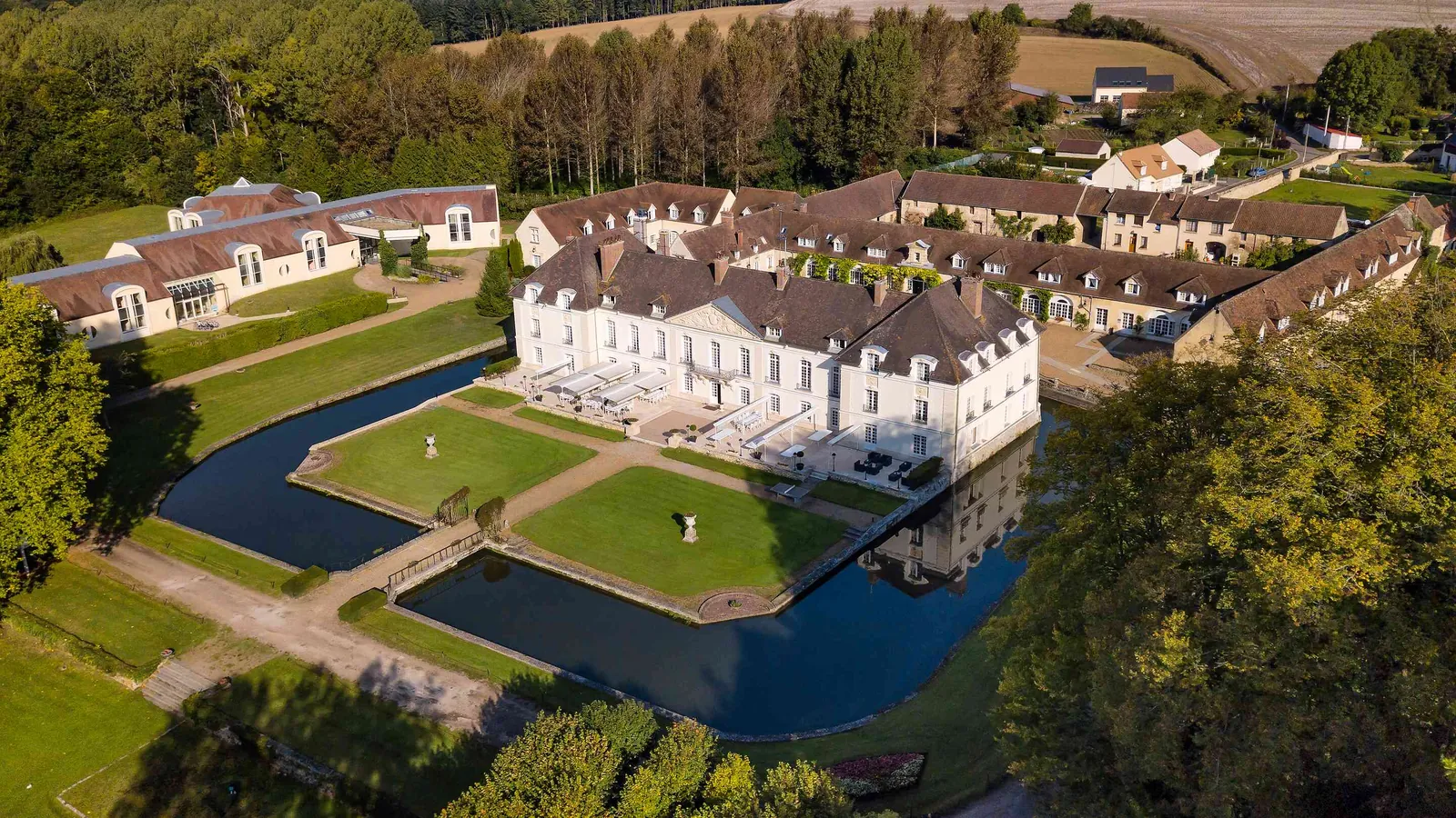 Aerial view of Château des Hauts Tilleuls with its outbuildings, gardens and rolling countryside in Oise