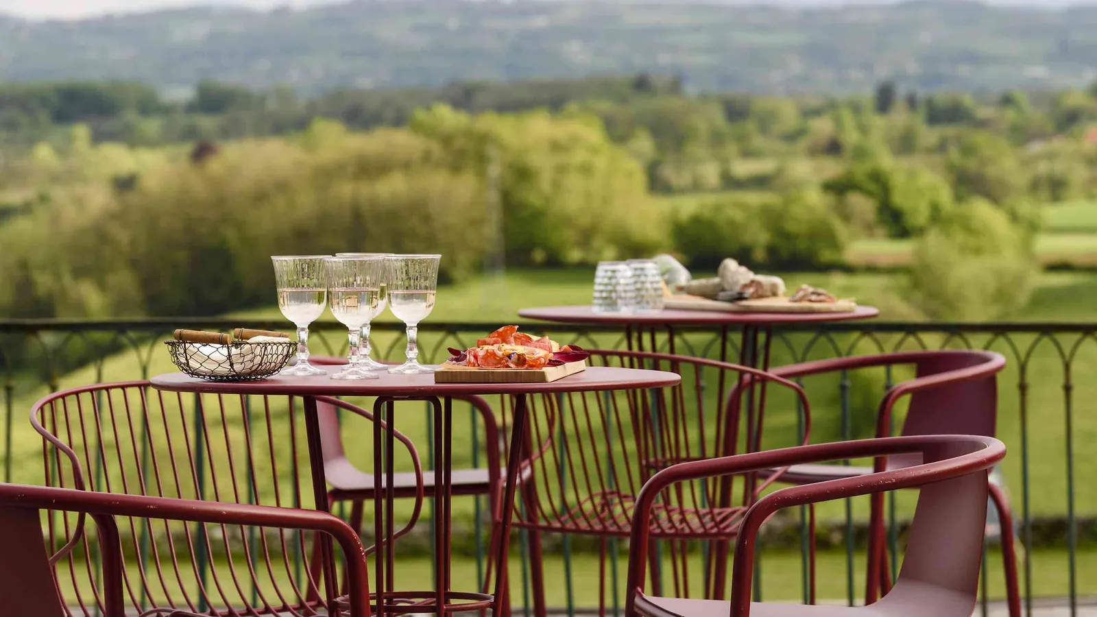 Terrace with wine glasses and a view over the countryside at Château des Quatre Vents, Isère