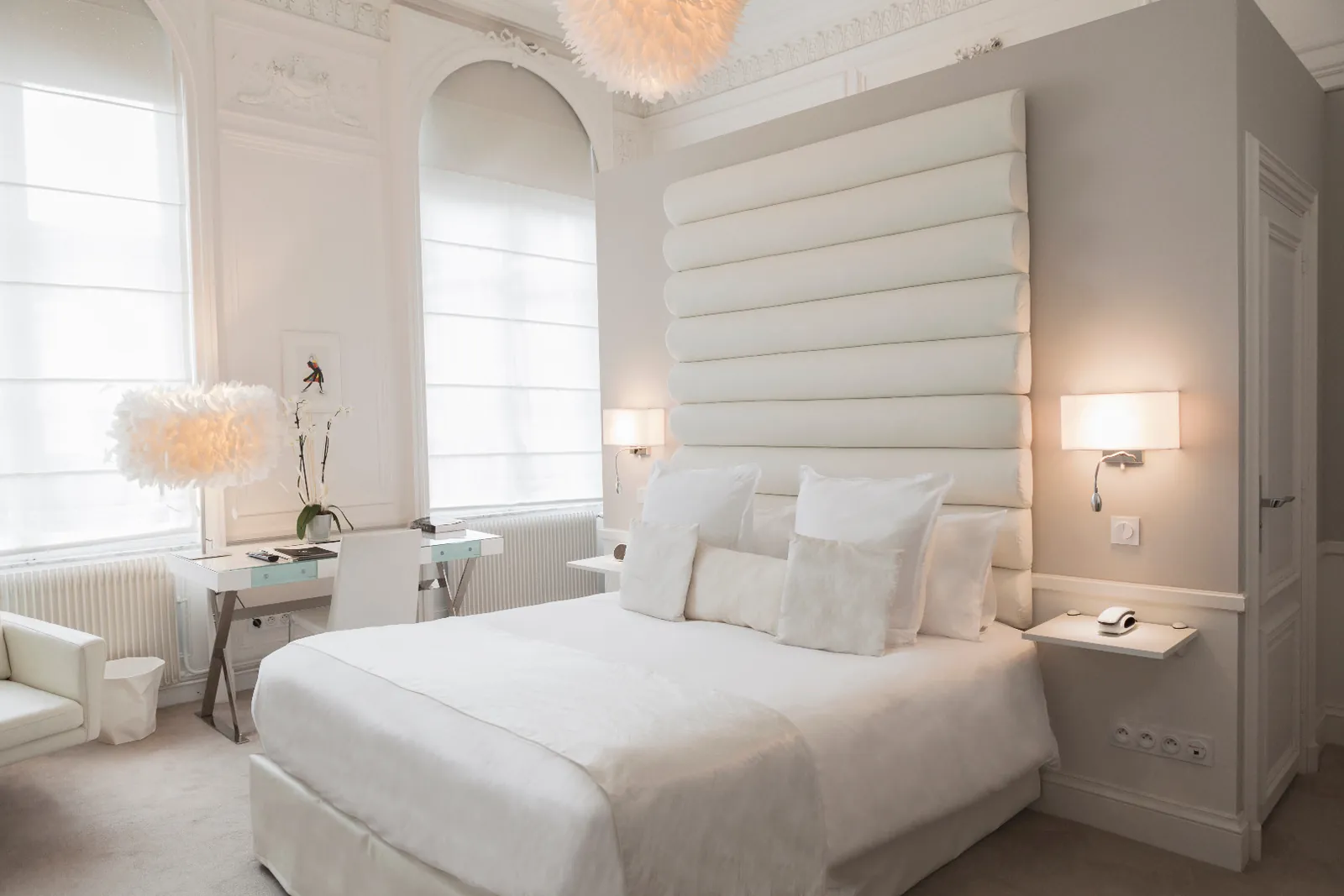 Bright guest room with a tufted white headboard and tall windows at Clarance Hôtel, Lille