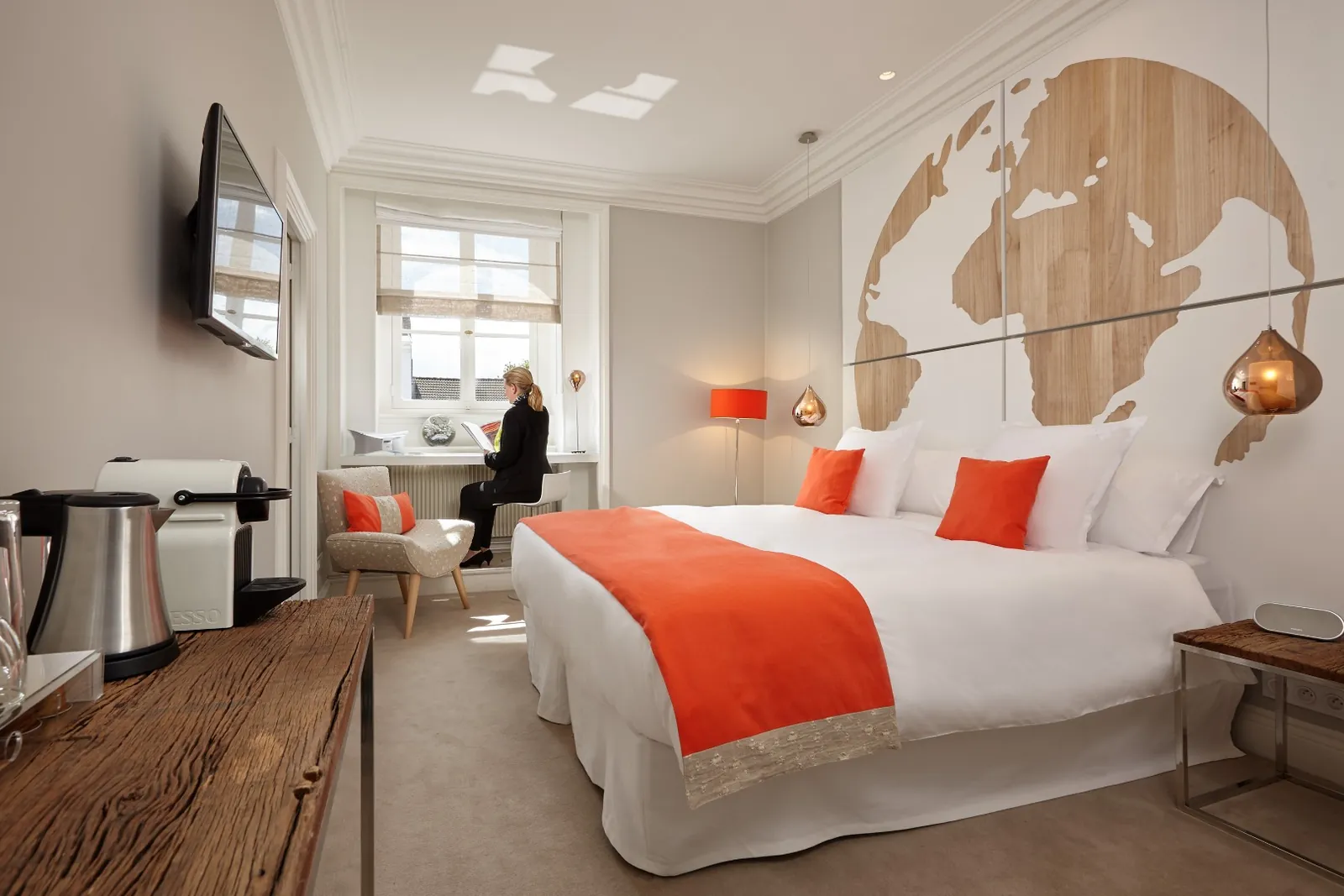Guest room with orange accents, a world-map panel and a flat-screen TV at Clarance Hôtel, Lille
