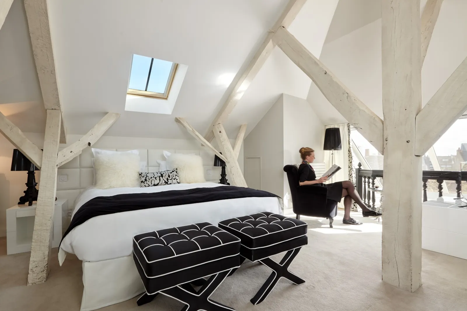 Loft suite with white beams, a skylight and black ottomans at Clarance Hôtel, Lille