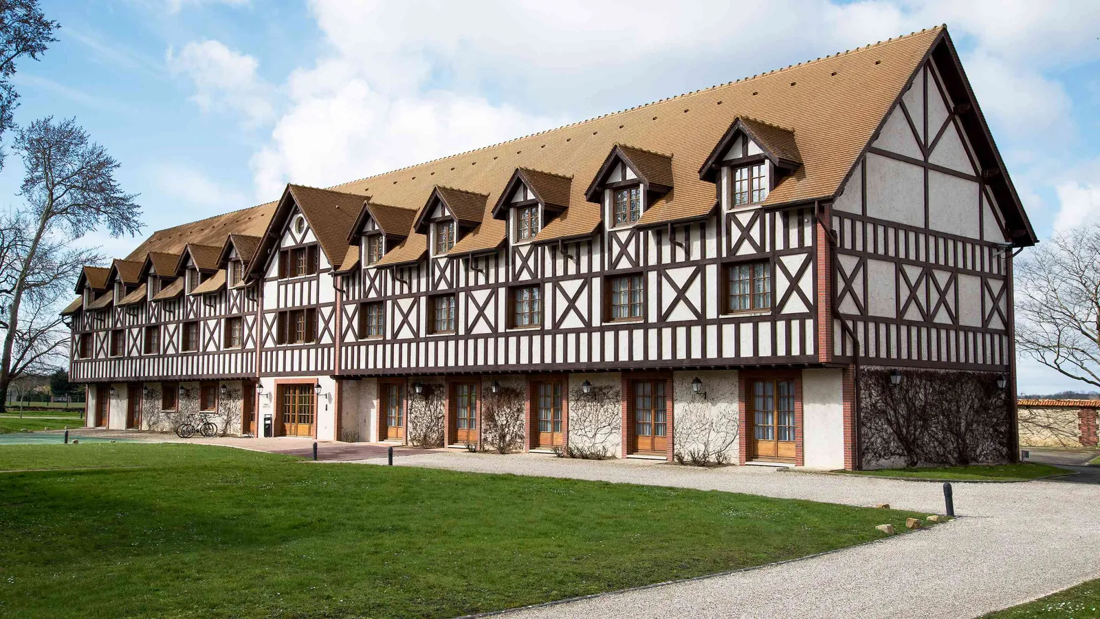 Long half-timbered building with dormer windows and lawns at Domaine de la Haute Futaie, Yvelines