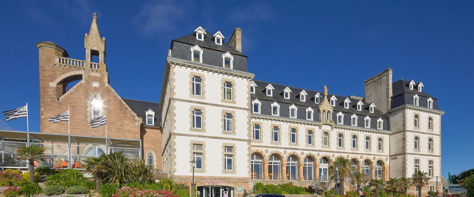 Traditional main building with a brick turret and Breton flags at Domaine des Embruns, north Brittany