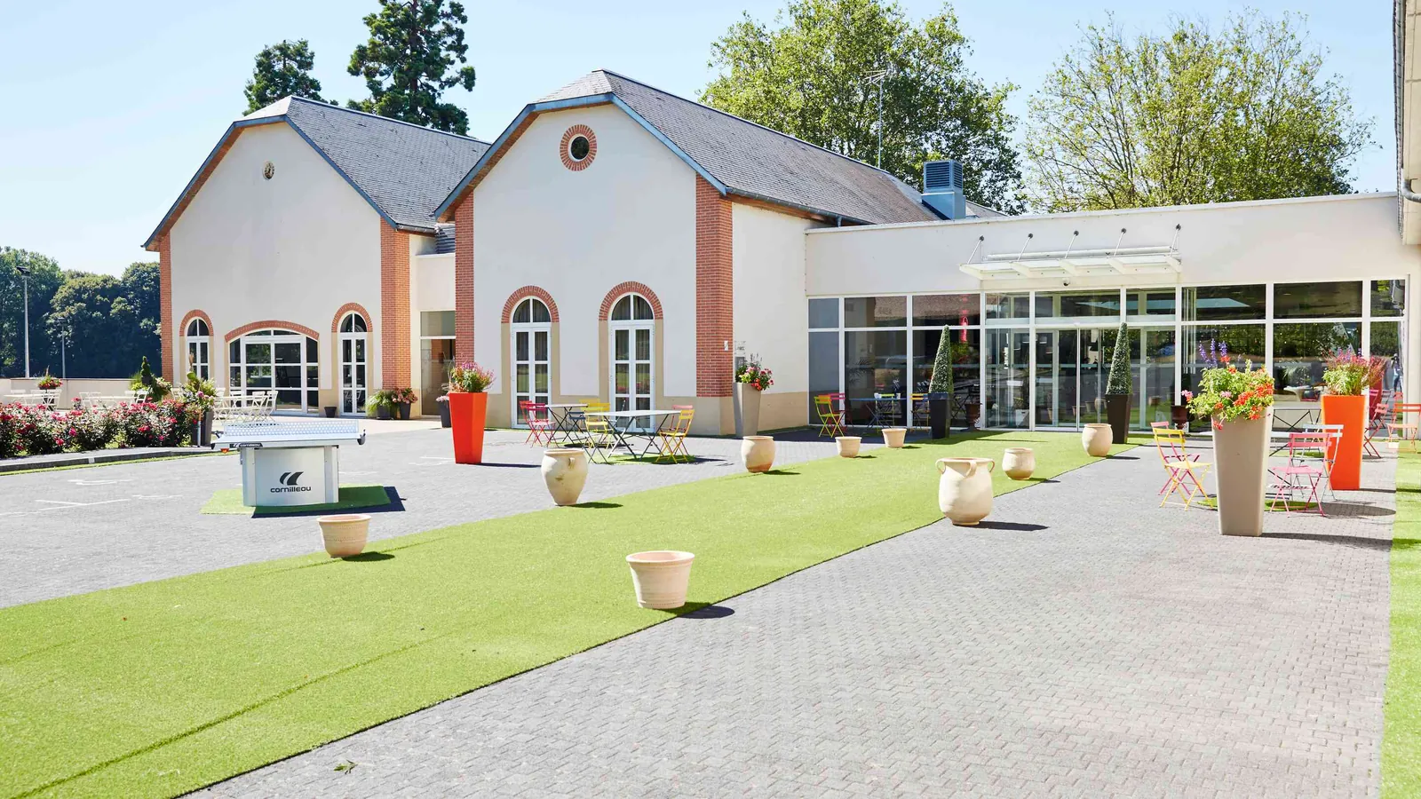 Glass-fronted pavilion and paved terrace with seating at Domaine des Hautes Clairières, Oise