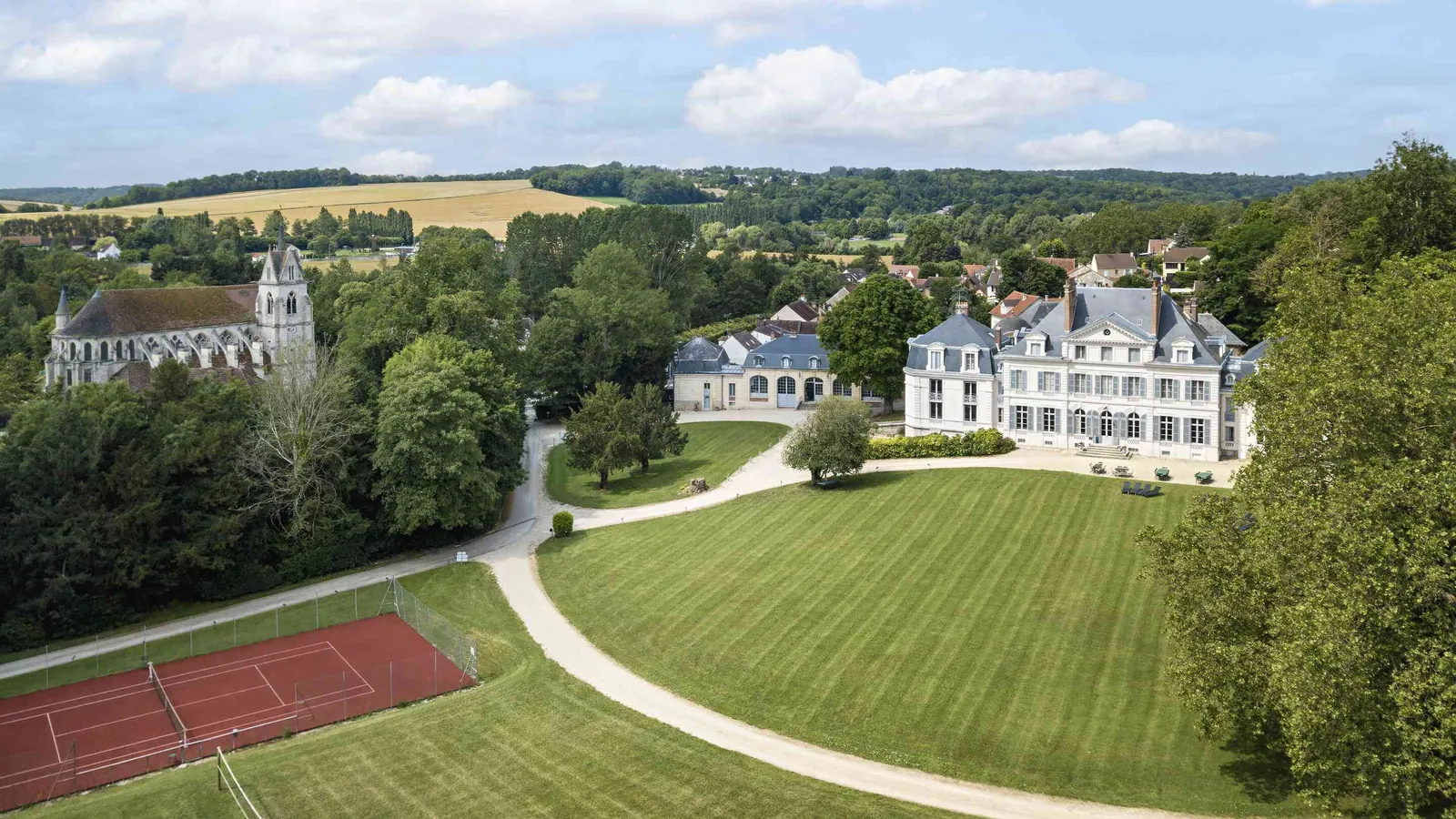 Aerial view of Domaine des Ormes Blancs with its château, wooded parkland and tennis court