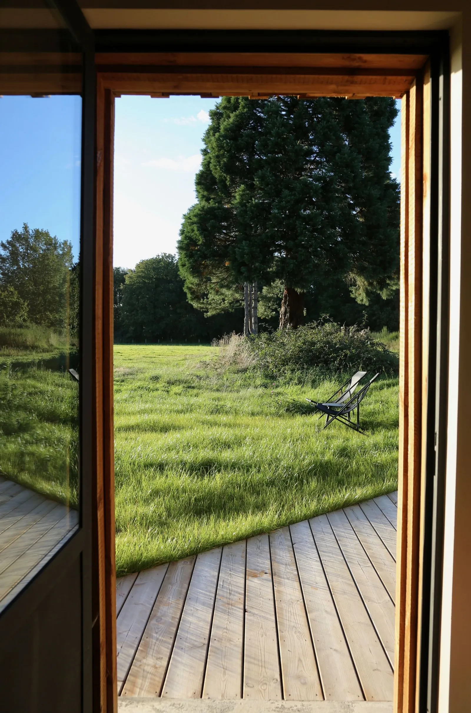 View from a tall wooden doorway onto the lawn at Domaine des Pigeonniers