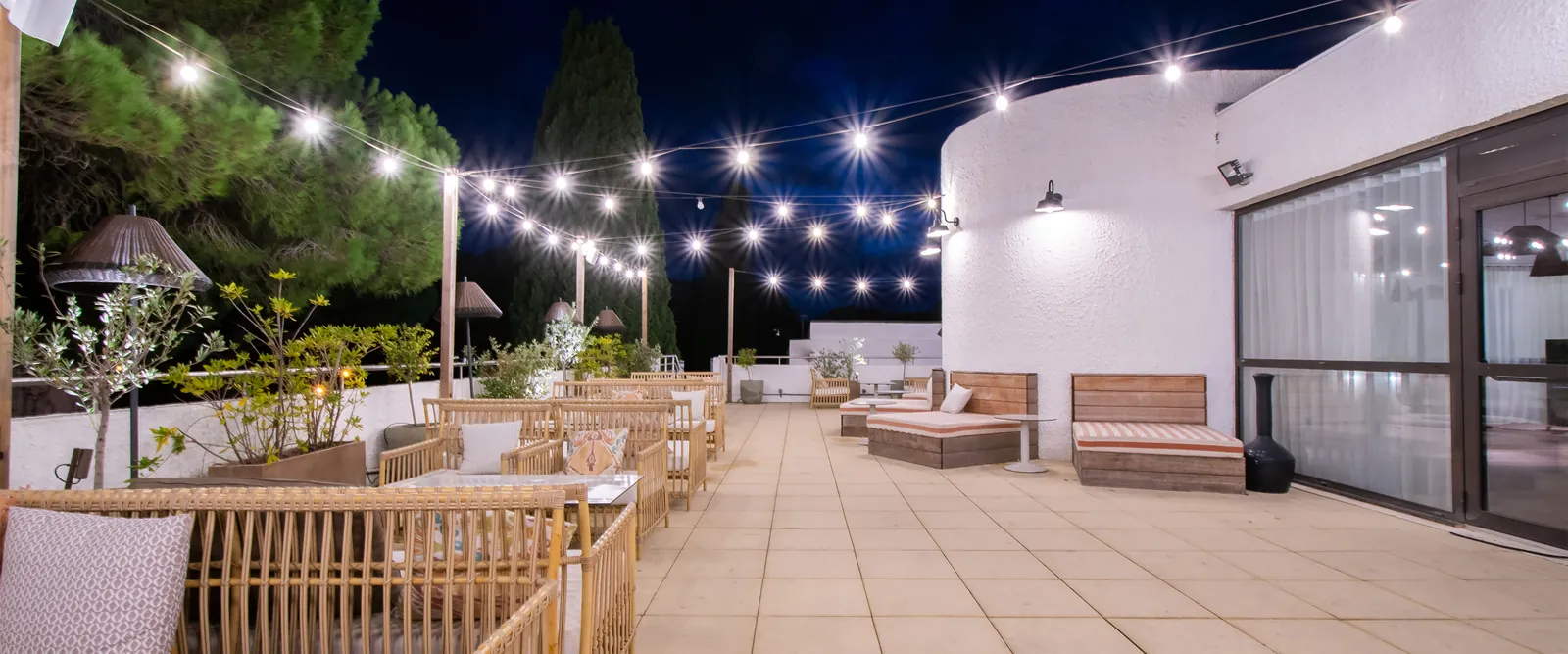 Evening terrace with string lights and wooden lounge seating at Domaine des Pinèdes Languedociennes, Hérault