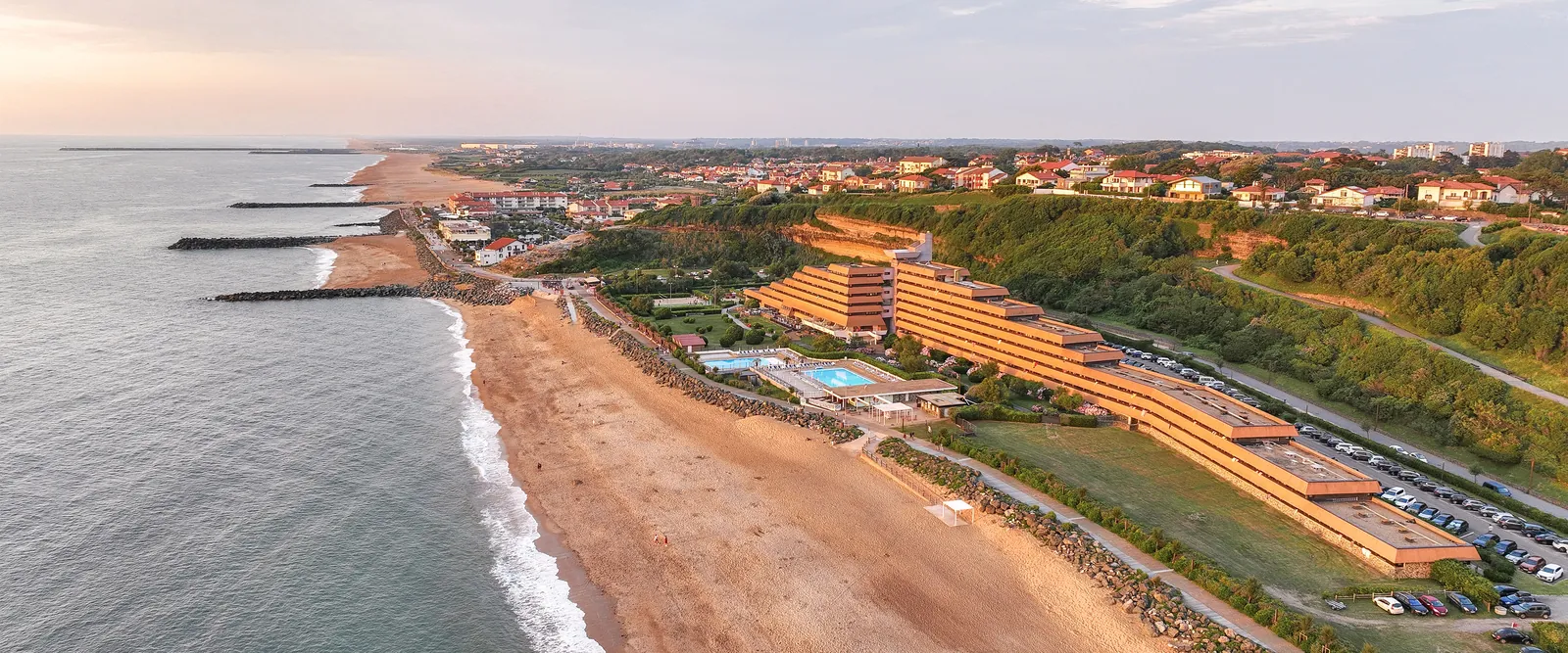 Coastline view of Domaine des Rivages Basques at sunset, with the resort above the sandy beach on the Basque coast