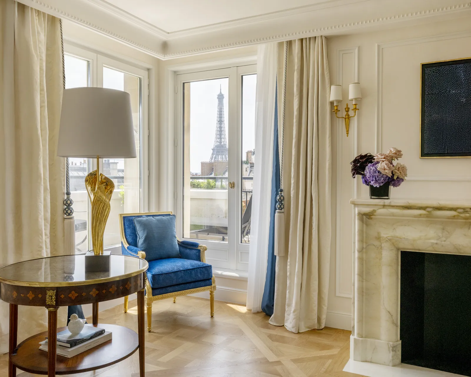 Suite living room with a blue armchair and an Eiffel Tower view at Four Seasons Hotel George V, Paris
