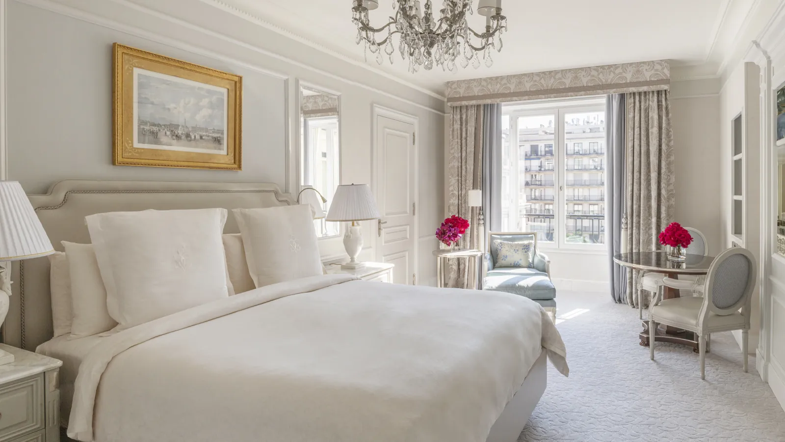 Bedroom with white bedding, gilded framed artwork and tall balcony doors at Four Seasons Hotel George V, Paris