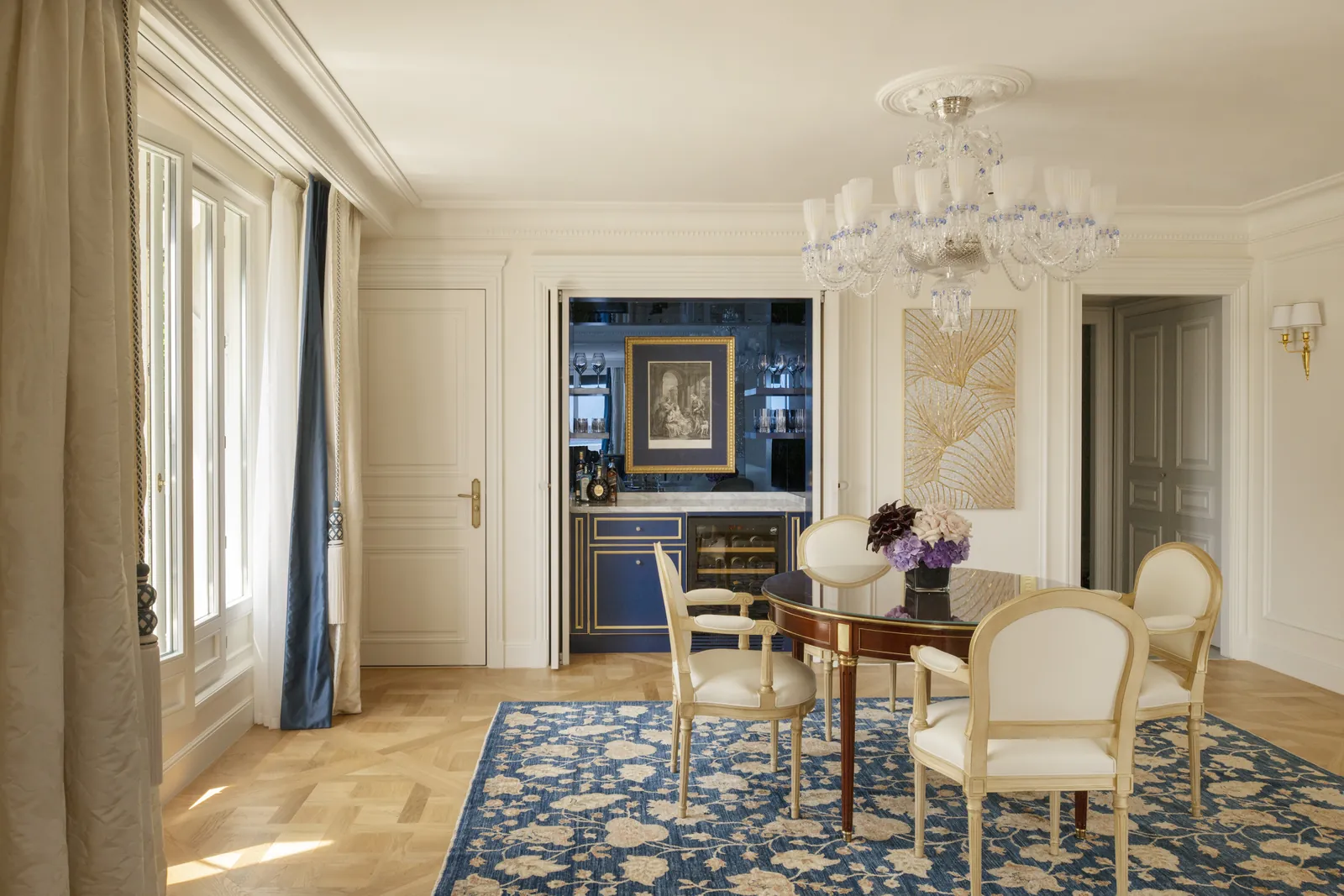 Dining area with a walnut table, cream chairs and a blue floral rug at Four Seasons Hotel George V, Paris