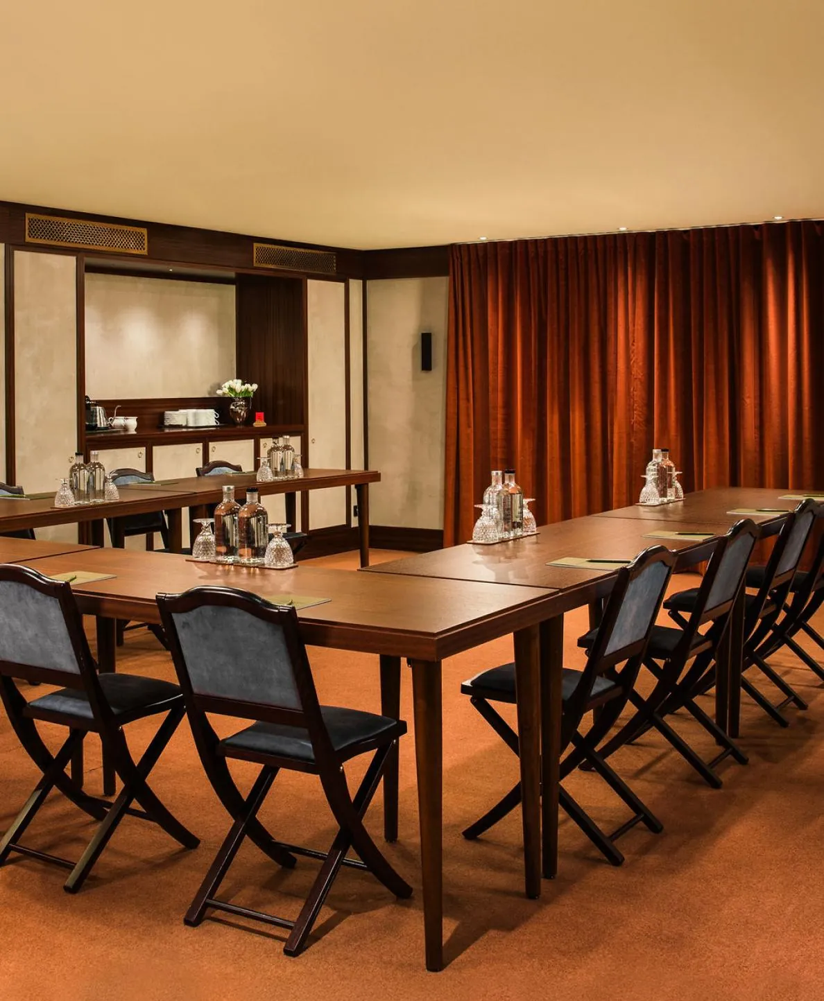Meeting room at Hôtel des Grands Voyageurs with a long table laid for a seminar and red velvet curtains