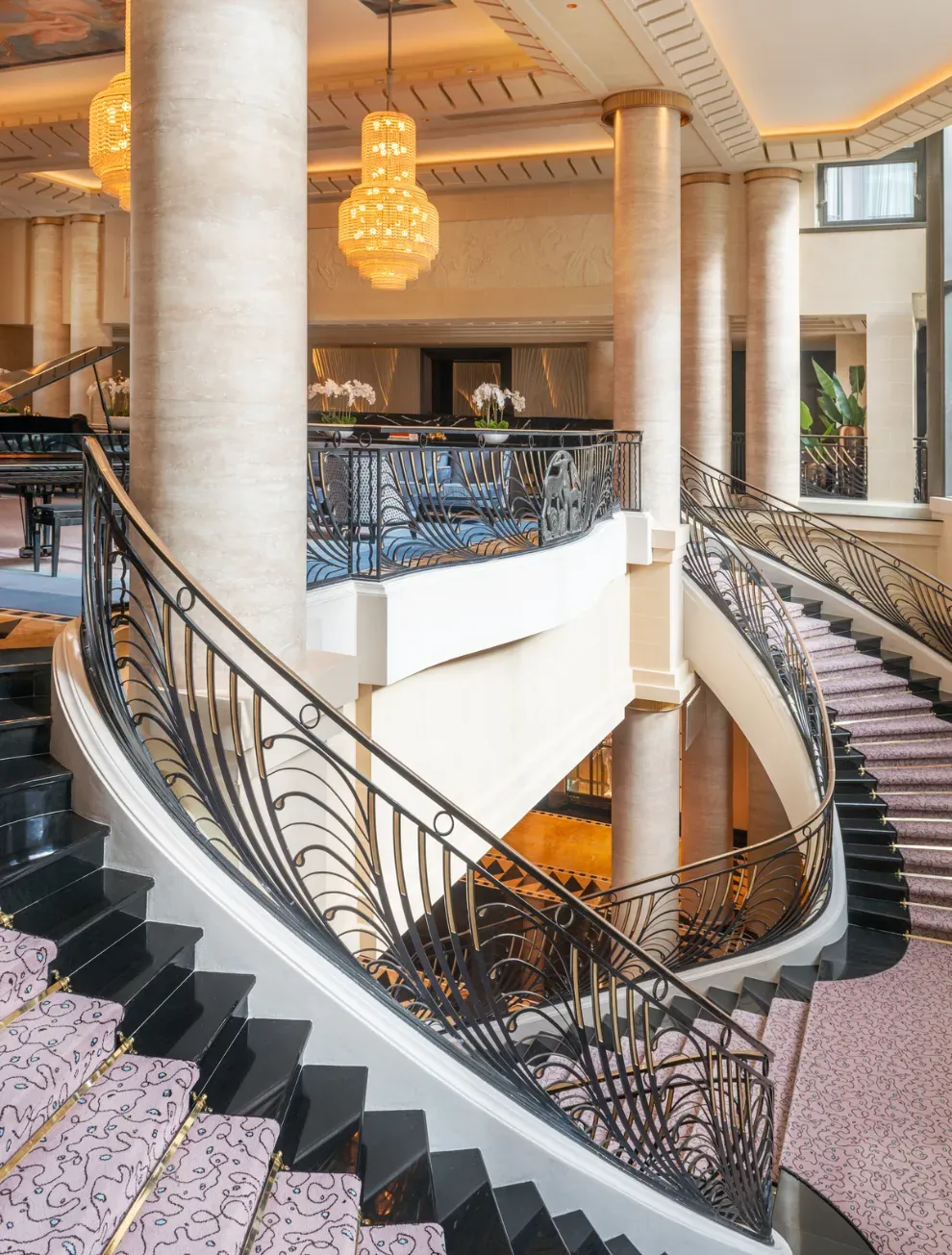 Sweeping Art Deco staircase with wrought-iron balustrade and chandeliers in the Hôtel du Collectionneur