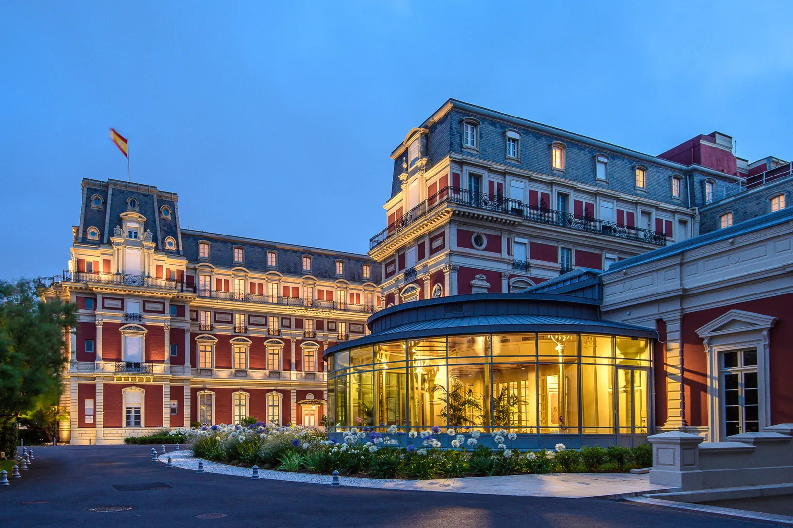 Grand hotel facade at dusk with its glass rotunda and lit windows, Hôtel du Palais, Biarritz