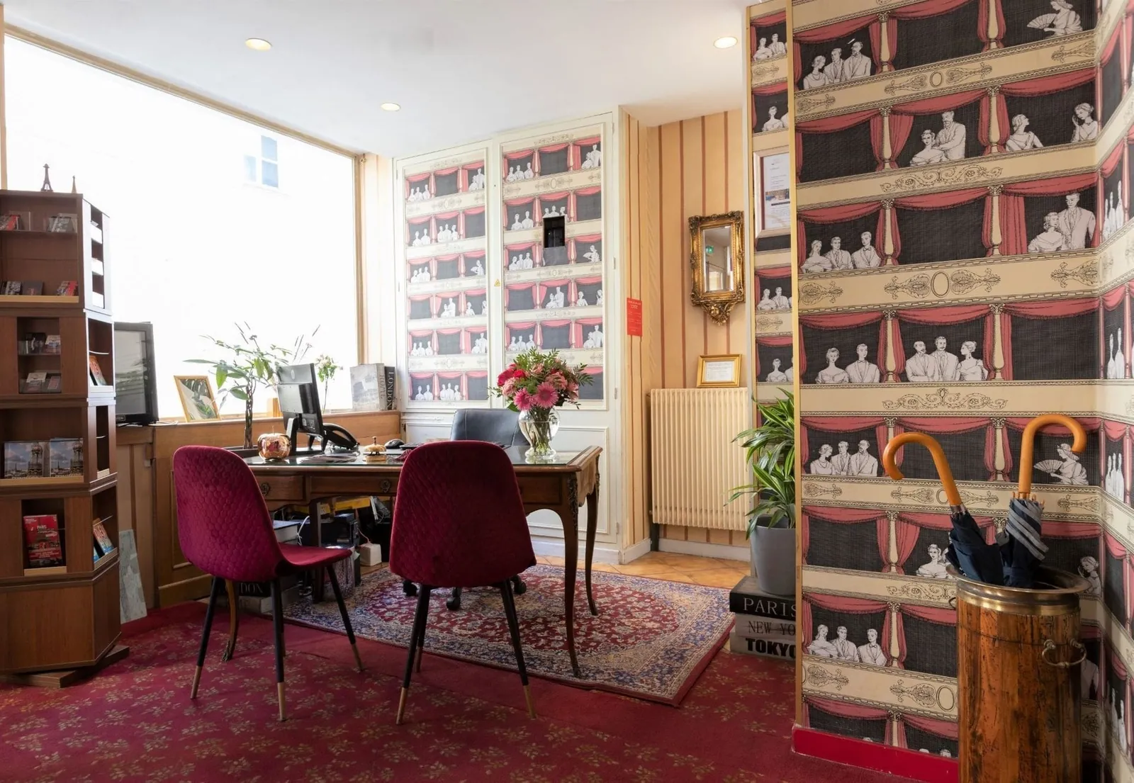 Reception and lounge corner of Hôtel du Théâtre with theatre-print wallpaper, a writing desk and armchairs