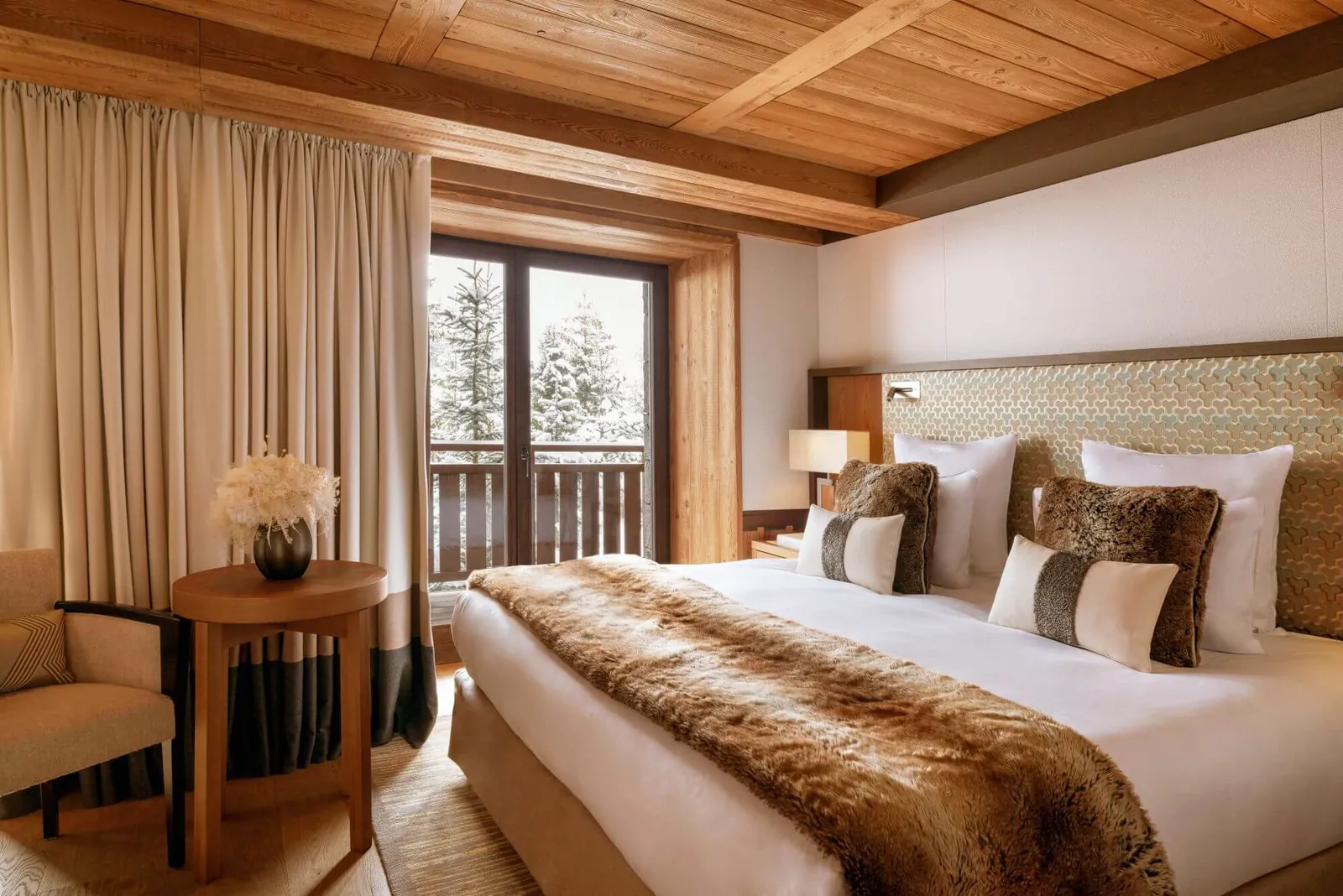 Superior bedroom with wooden ceiling, fur throw and balcony door at Hôtel Fouquet's Courchevel