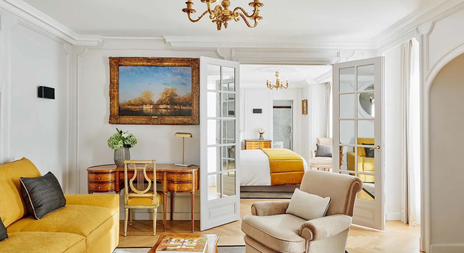 Suite with a yellow sofa, painted landscape and French doors at Hôtel Lancaster Paris