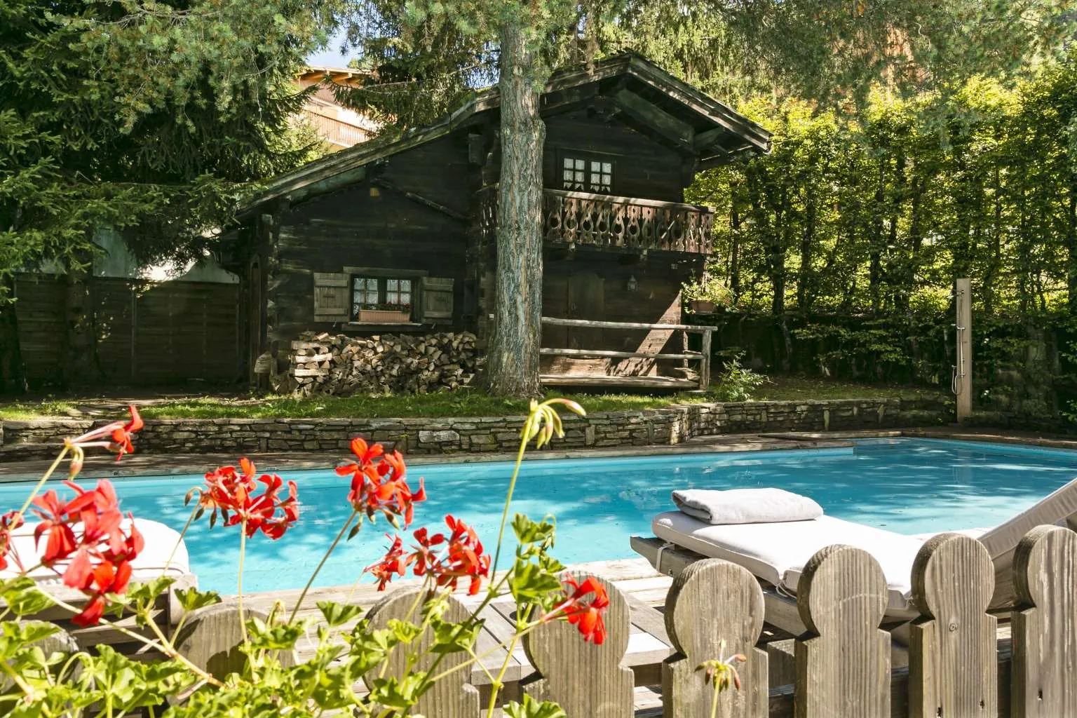 Outdoor heated pool beside the chalet-style hotel building at Hôtel Le Fer à Cheval, Megève