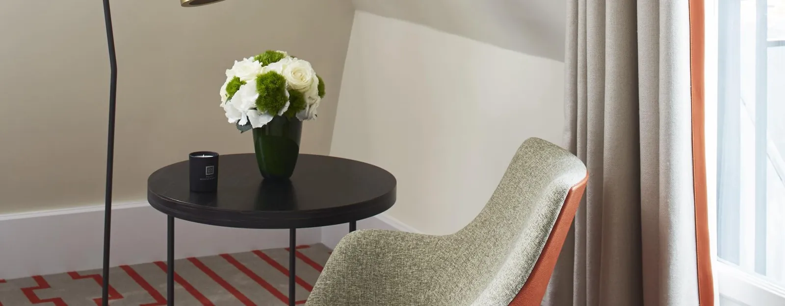 Guest room at Hôtel Montalembert Paris with a sage armchair, a round side table and a large window in the 7th arrondissement