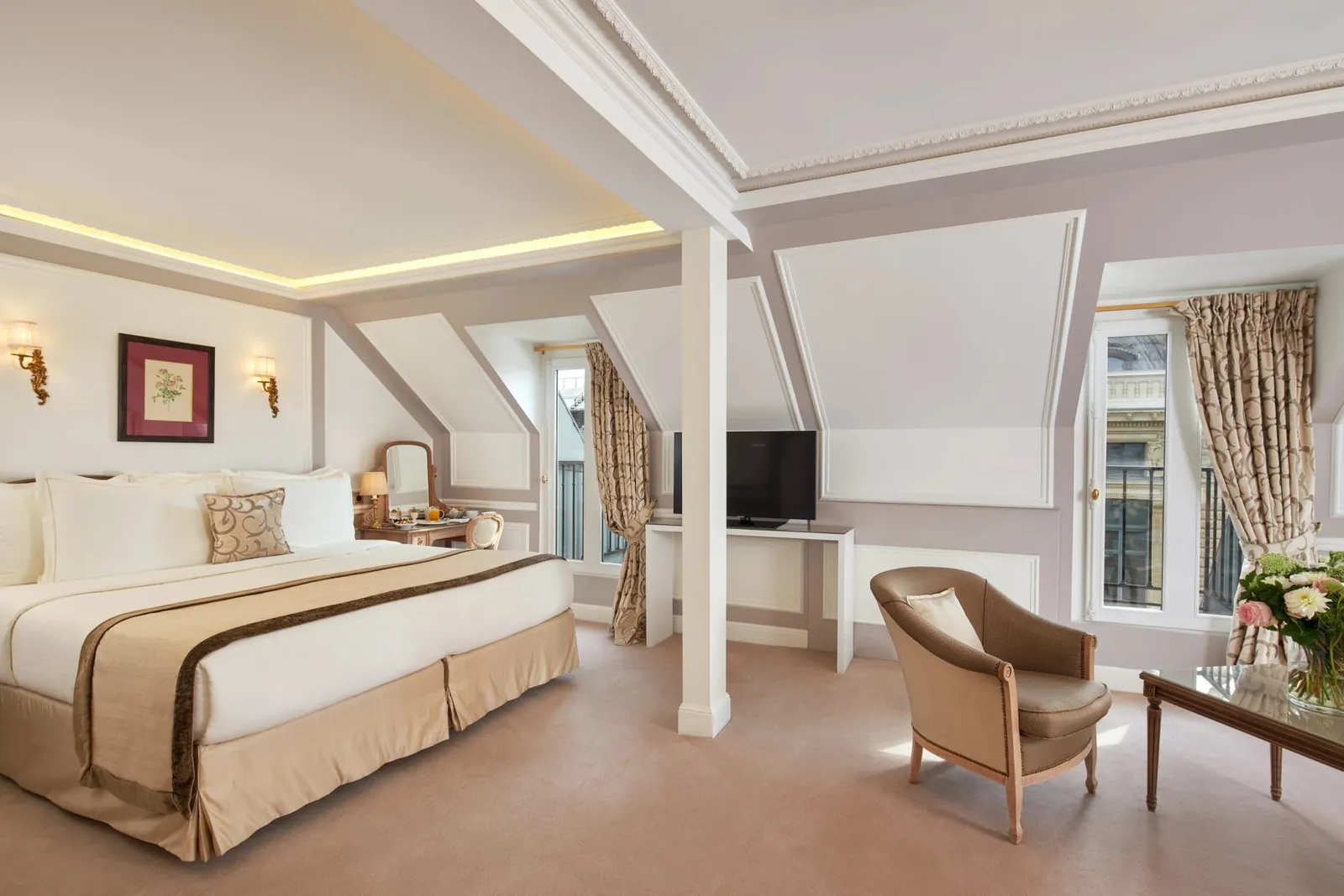 Junior suite with a sofa and armchair beside tall windows at Hôtel Regina Louvre, Paris