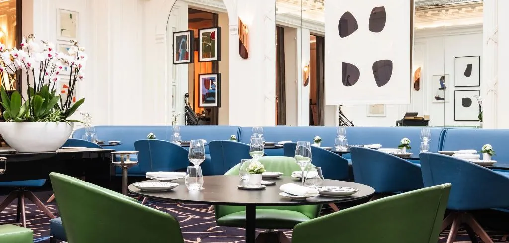 Restaurant Le V at Hôtel Vernet in Paris, with blue banquettes, green chairs and orchids on the tables