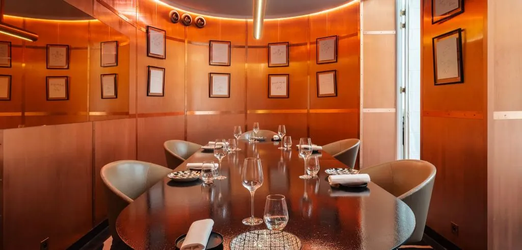 Private dining room at Hôtel Vernet in Paris with wood-panelled walls and a round table set for dinner