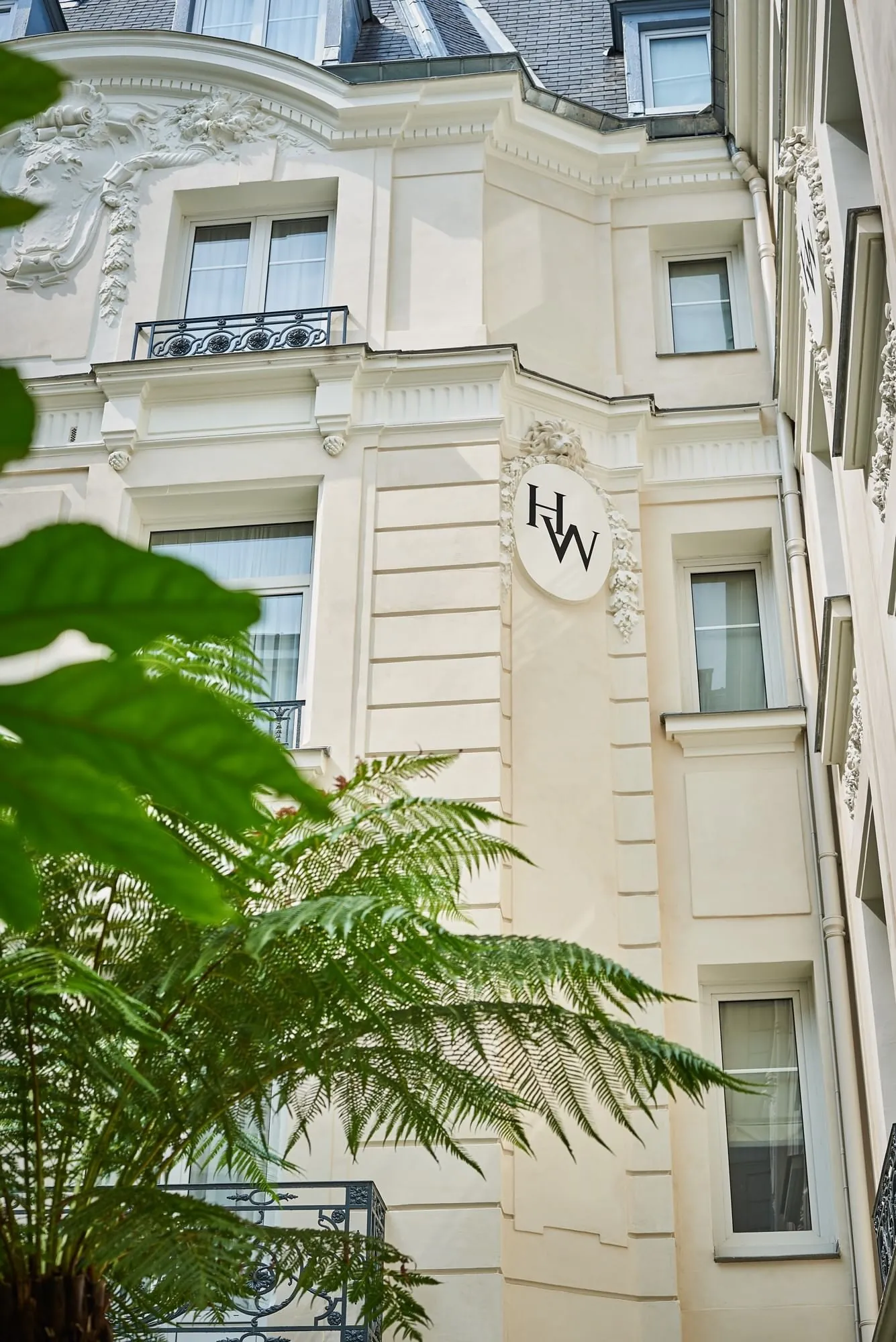 Facade of Hôtel Westminster in Paris, a cream stone building with a W monogram and greenery in front
