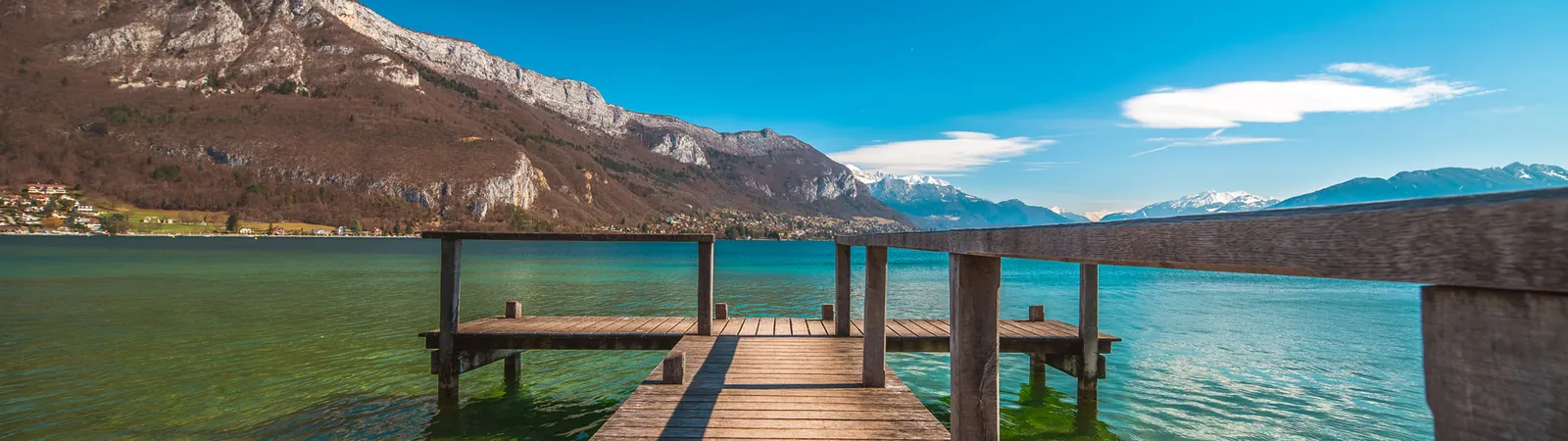 Wooden jetty stretching into the calm water of Lake Annecy, with mountains behind
