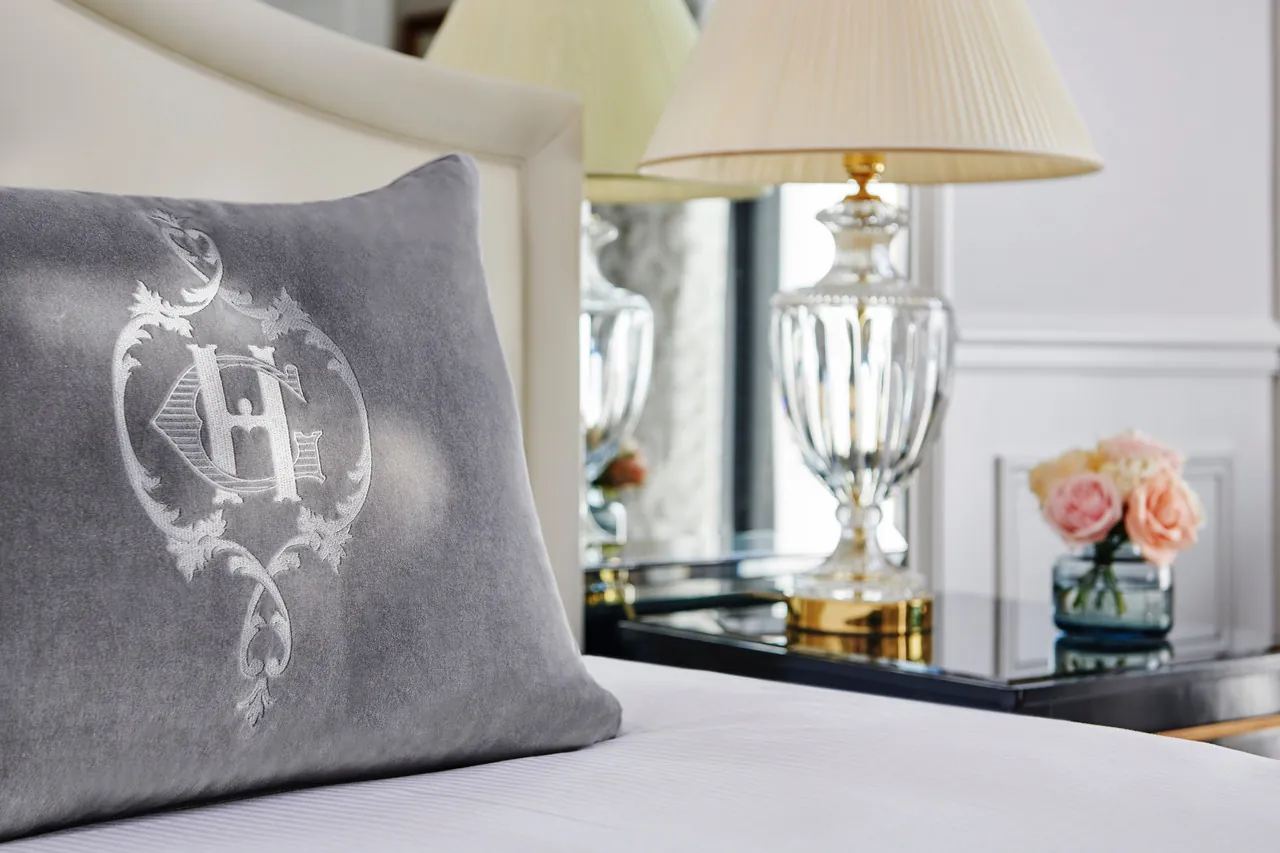 Grey cushion with a silver monogram beside a lamp in a room at InterContinental Paris Le Grand
