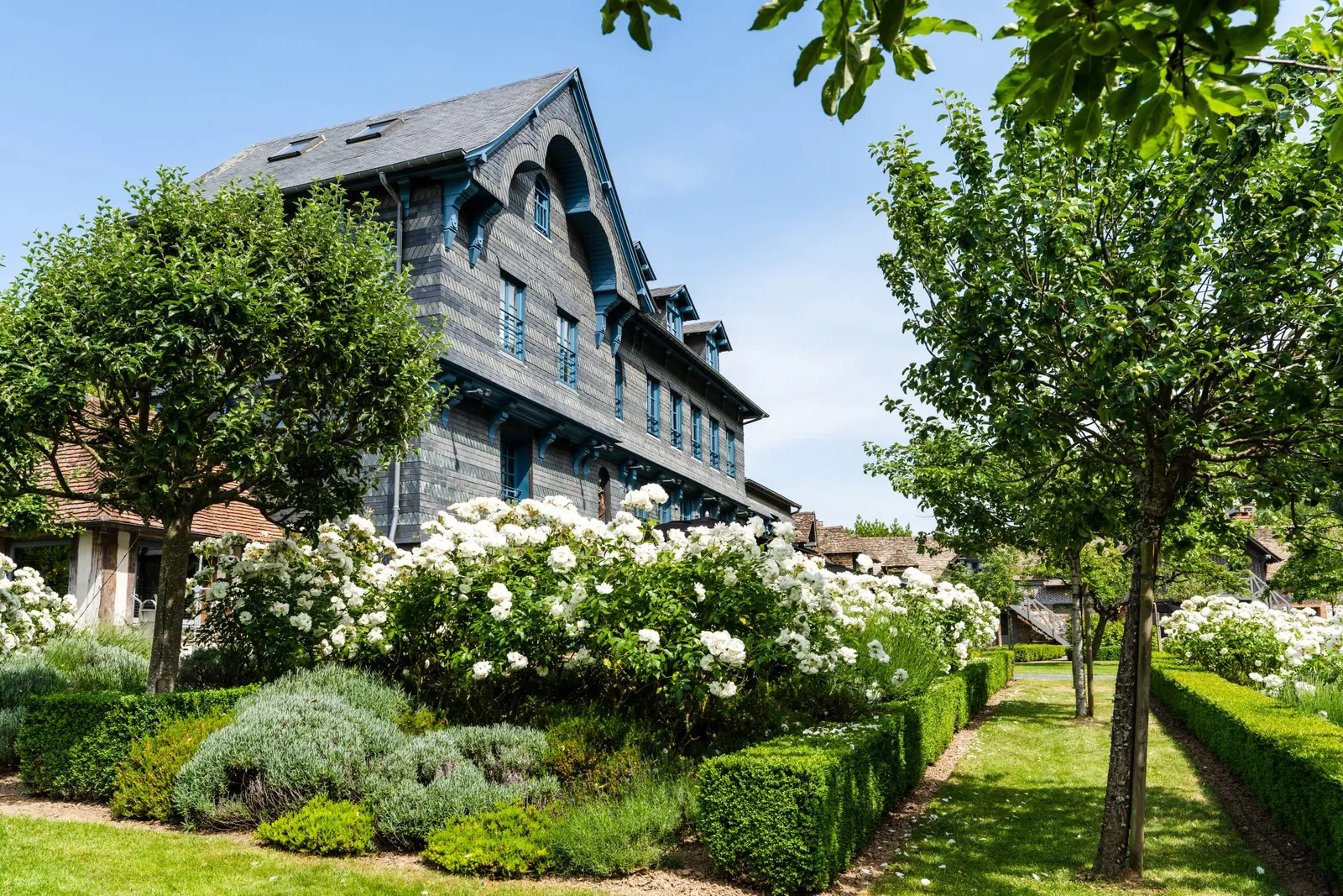 Slate-clad historic house and clipped garden with hydrangeas at La Ferme Saint-Siméon, Honfleur