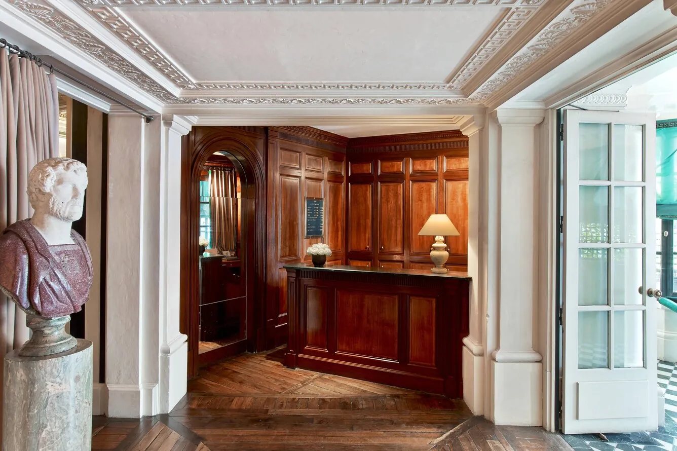 Entrance lobby of Le Dokhan's Paris with dark wood panelling, a marble bust and herringbone parquet floors