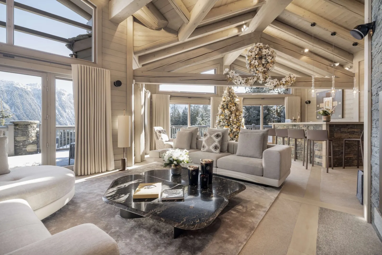 Living room of a Le K2 Palace chalet with pale timber beams, a dark marble coffee table and mountain views