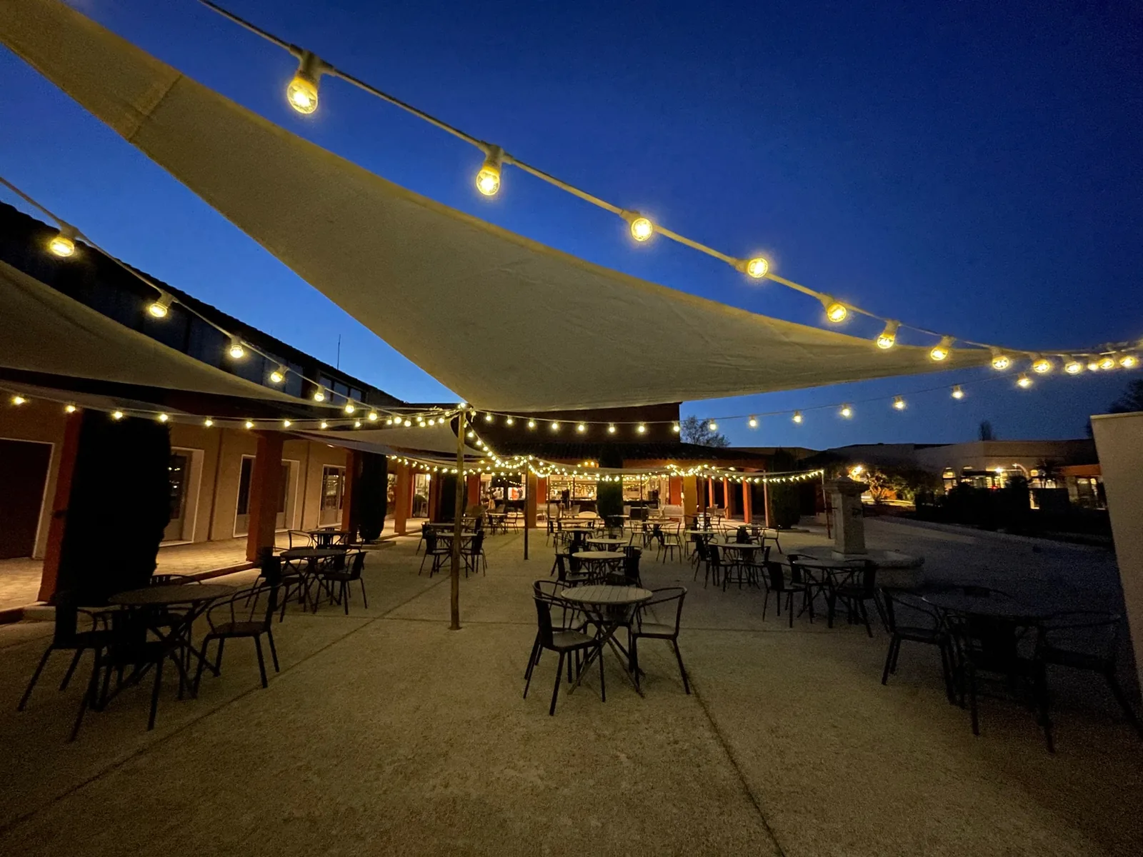 Evening terrace under string lights and sail canopies at the Village Camarguais in Arles