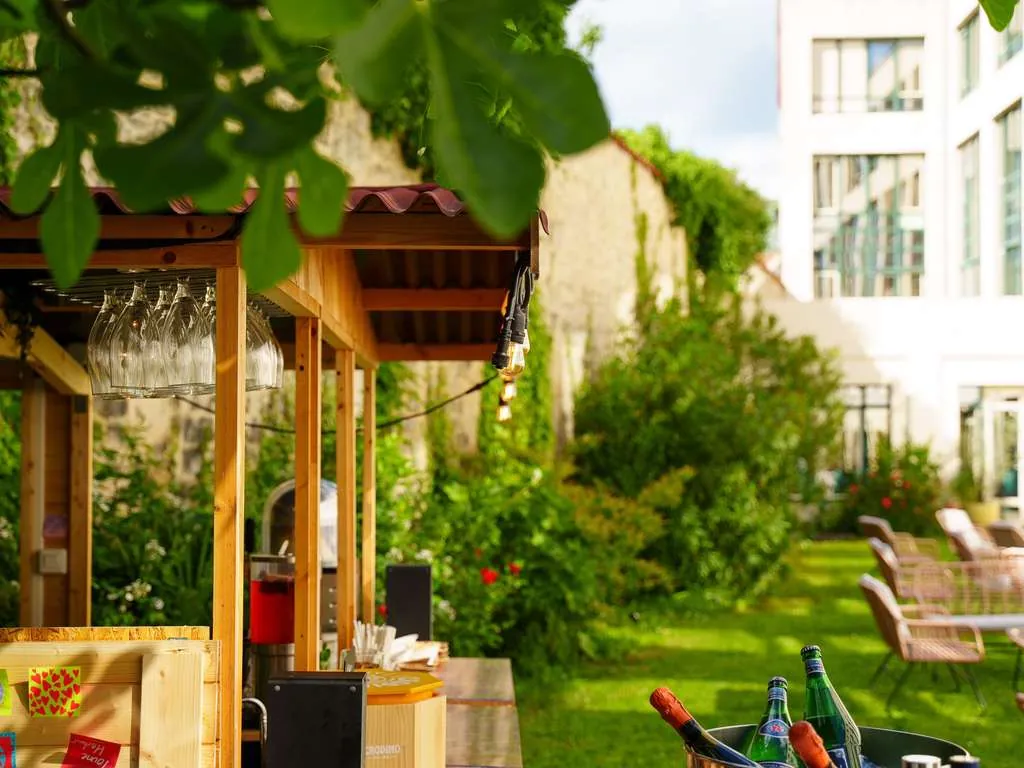 Garden terrace with lawn, wooden bar counter and climbing ivy at Mercure Bordeaux Château Chartrons