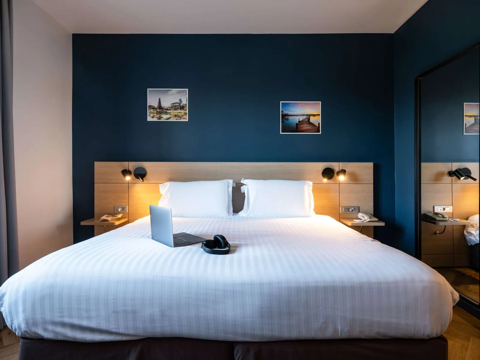 Guest room at the Mercure Chantilly with a king bed, navy feature wall and wall-mounted reading lights