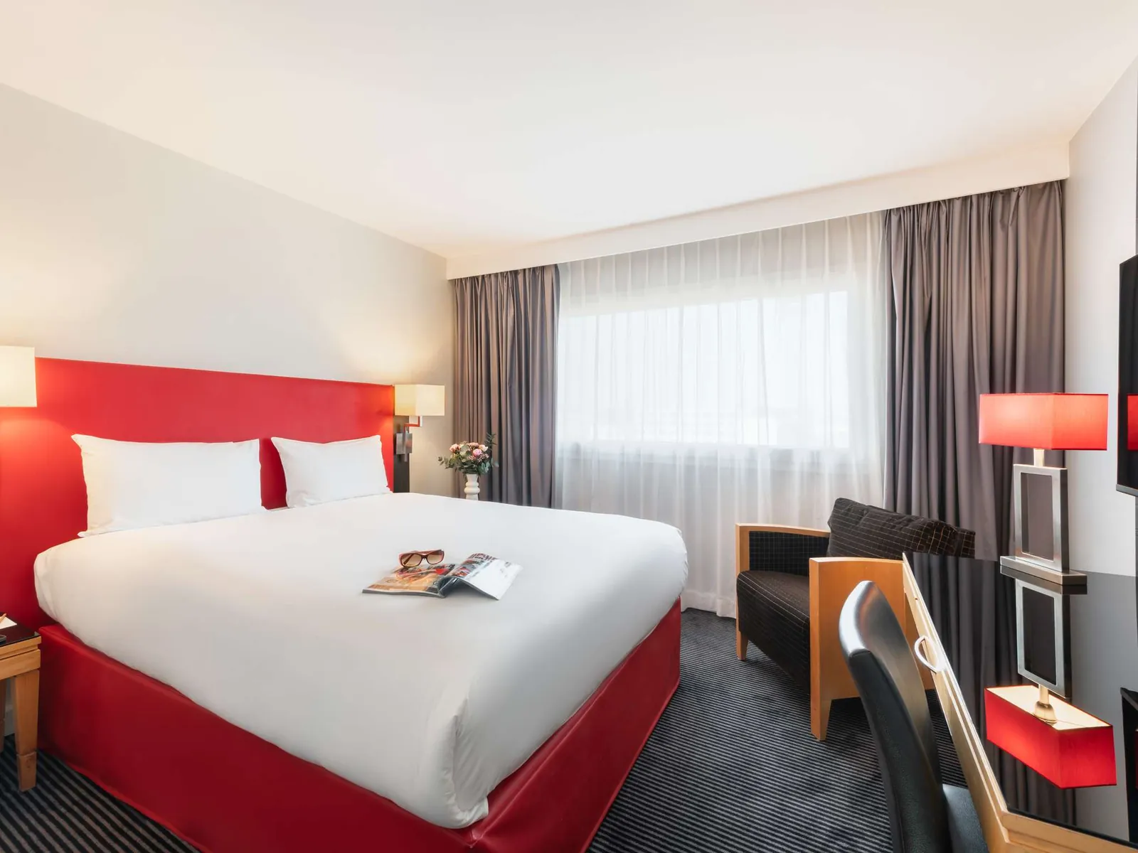 Standard double room at Mercure Paris CDG Airport with a red headboard and a grey armchair