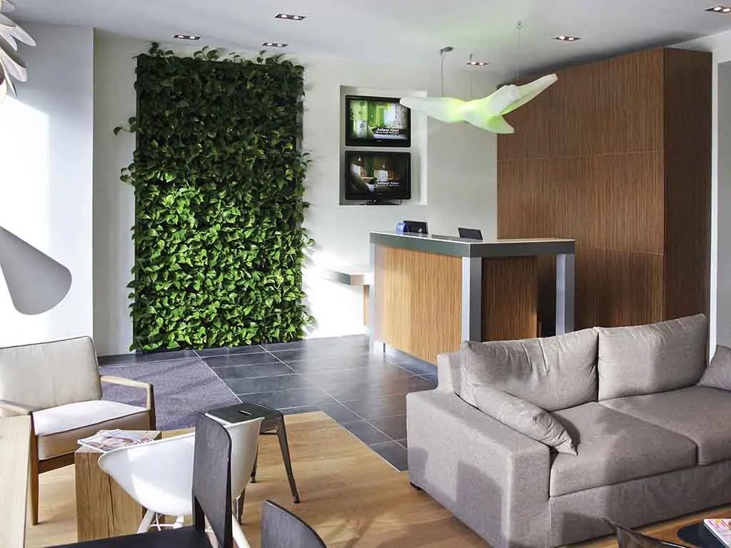 Reception lounge of Mercure Paris Gare du Nord La Fayette with a living wall of plants and grey sofas