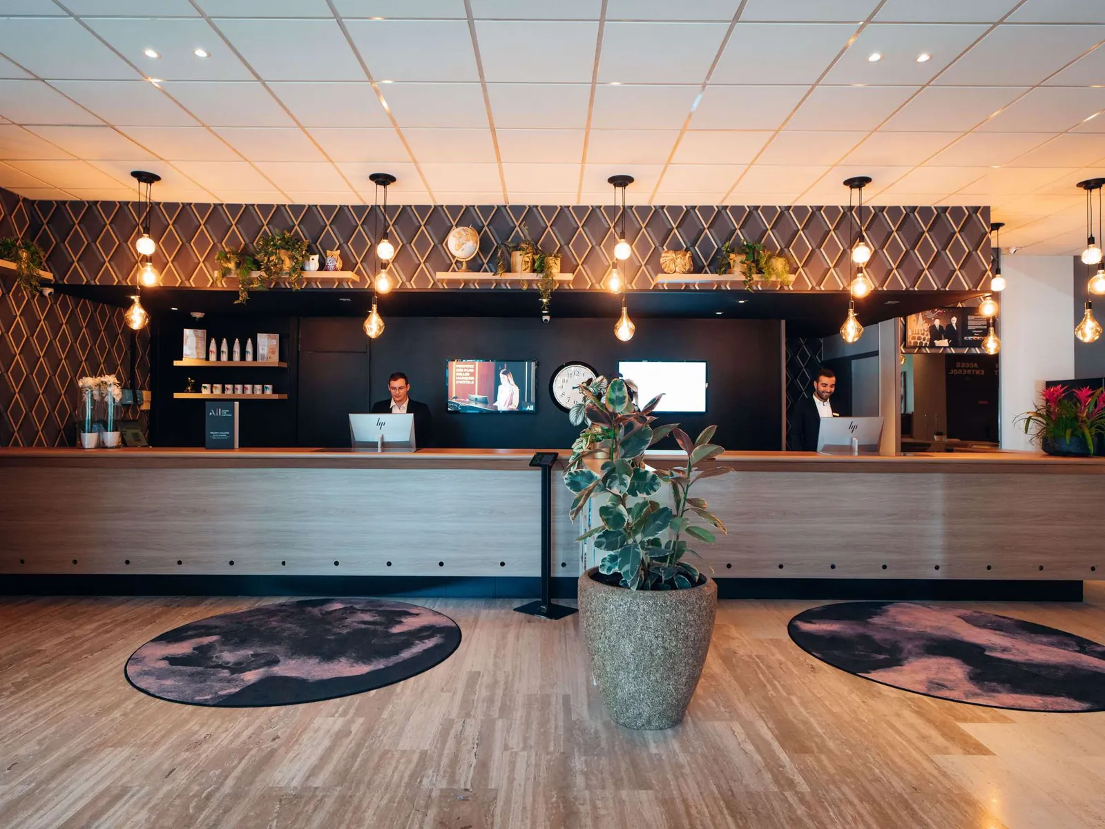 Reception desk with pendant lights and a warm wooden floor in the lobby of Mercure Paris Orly Rungis Airport