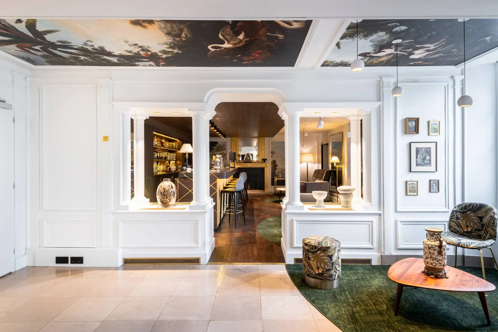 Lobby of the MGallery Aigle Noir in Fontainebleau with painted ceiling, white panelling and a green rug