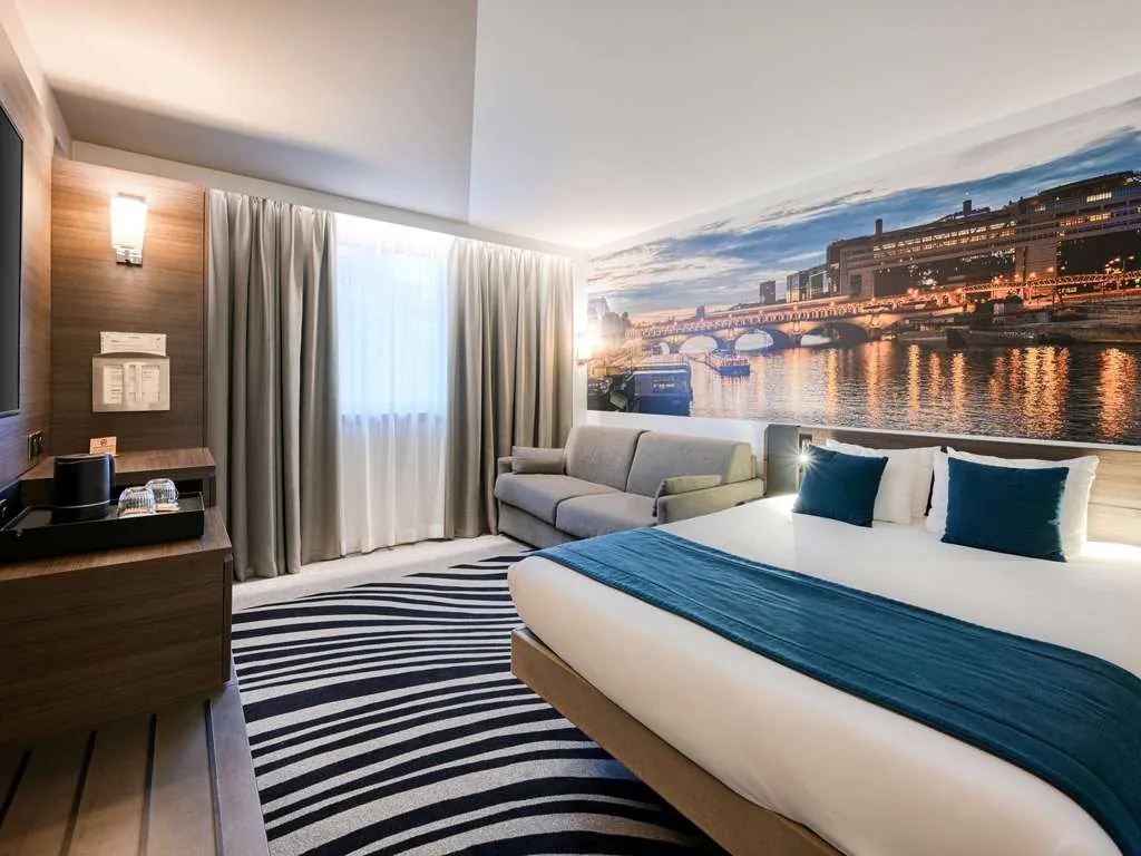 Double room with river-view wall mural, blue throw and striped rug at Novotel Paris Centre Bercy