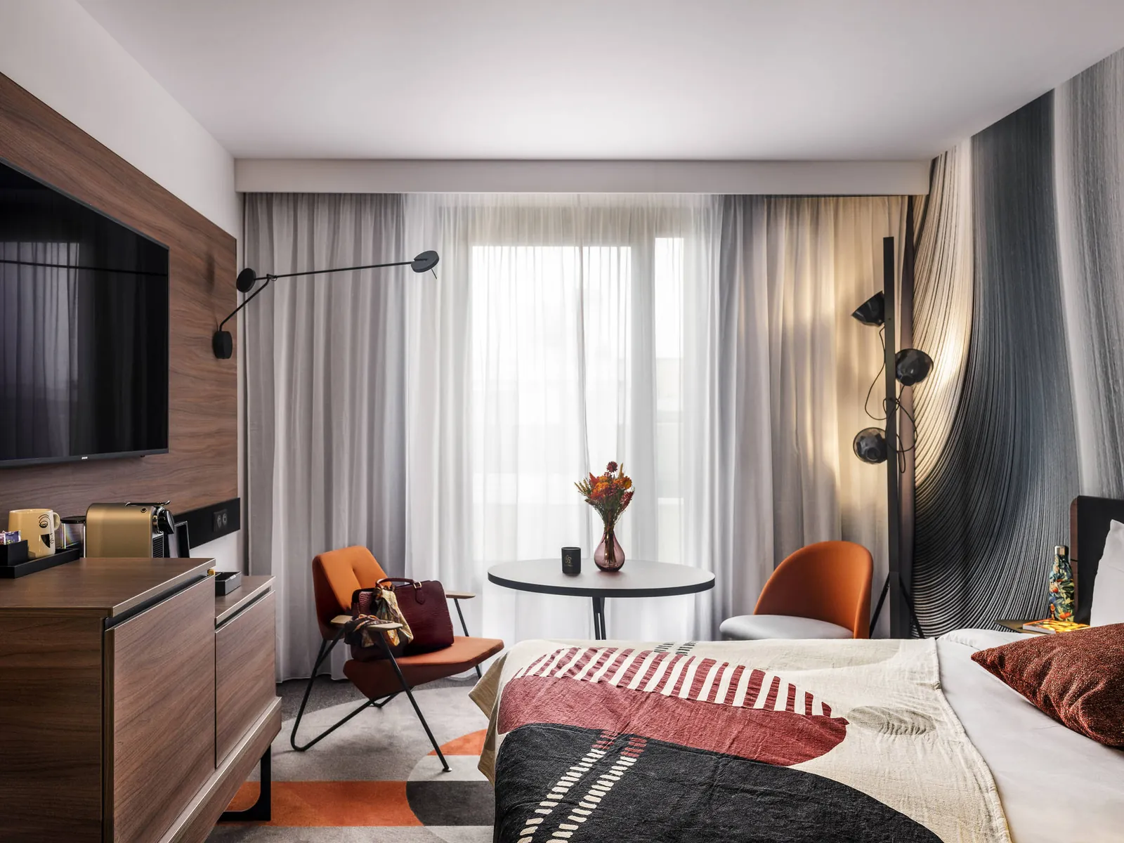 Bedroom with curved wall art, an orange armchair and a wooden desk at Novotel Paris Vaugirard Montparnasse