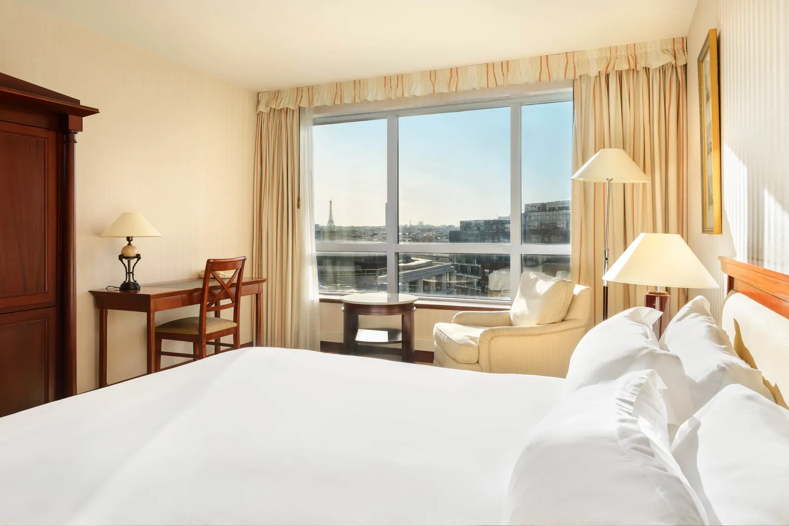 Deluxe room with a window seat and armchair by the window at Occidental Paris Levallois