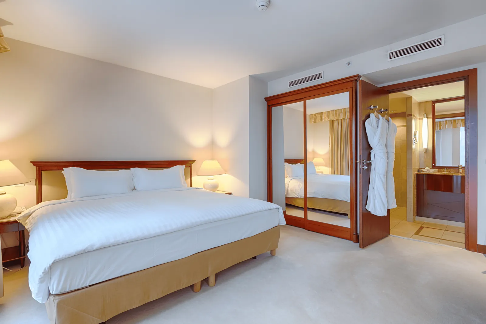 Junior suite with a king bed, mirrored wardrobe and bathroom in view at Occidental Paris Levallois